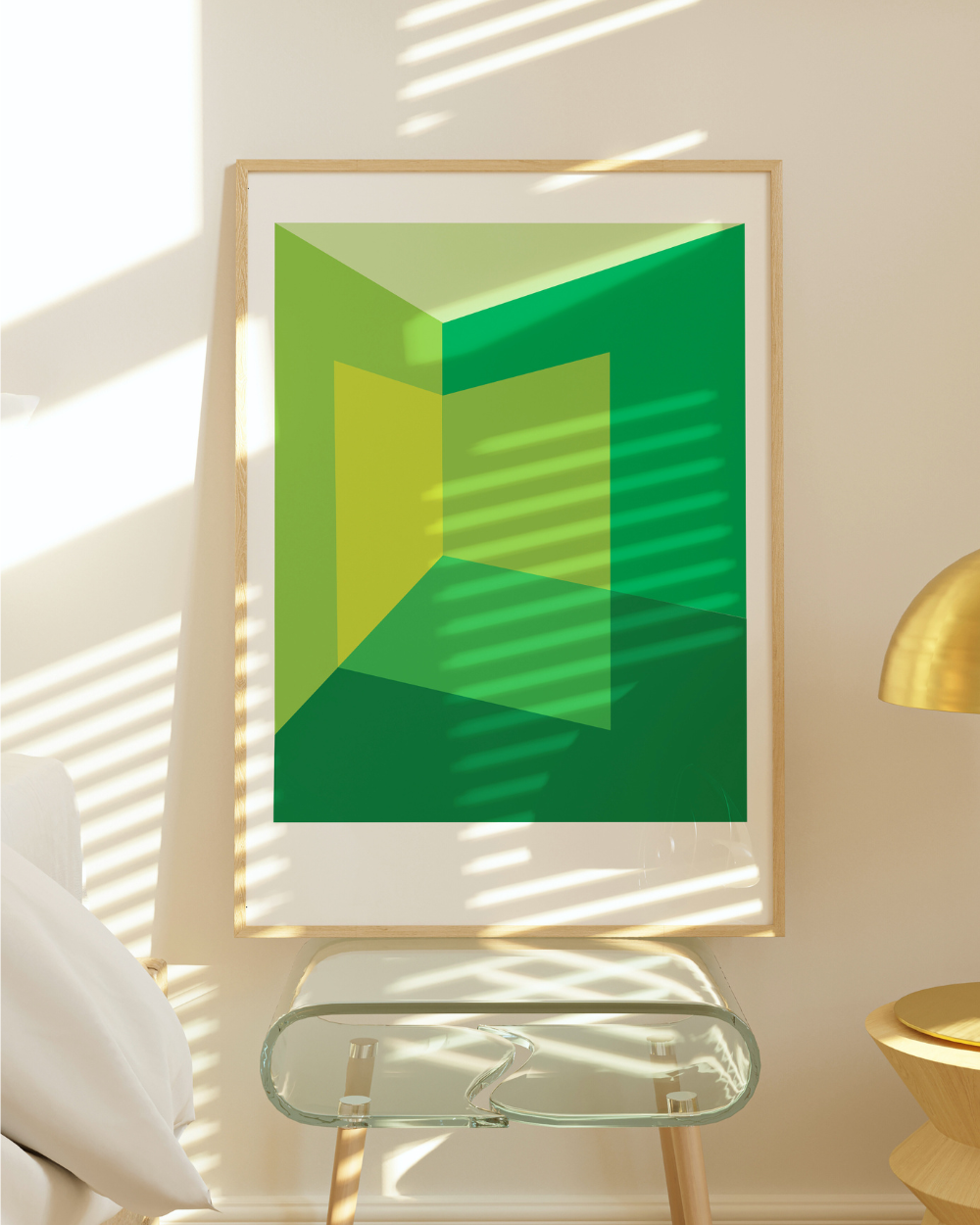 Framed abstract green artwork on a wall with natural light casting shadows.