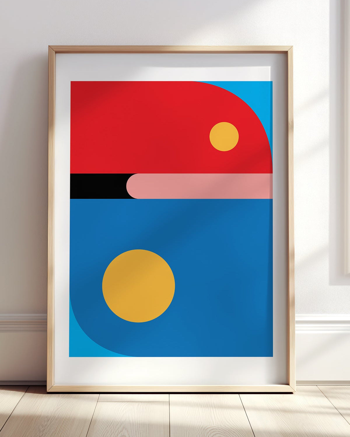 Abstract art print with geometric shapes in red, blue, yellow, and pink on a white wall.